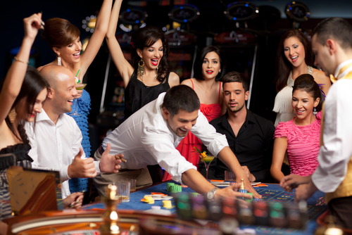 joueur masculin entouré d'un groupe de personne à une table de jeu